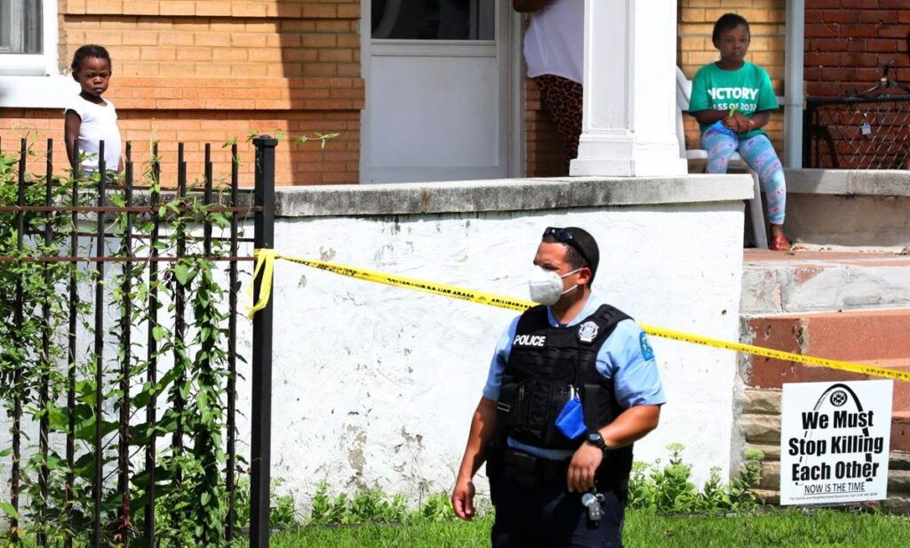 Children watch as St. Louis police officers investigate the shooting of their neighbor, a girl under a year old, in the 1300 block of Temple Place in Hamilton Heights on Friday, Aug. 14, 2020. The girl was reported to be shot in the arm and was taken to the hospital by officers.